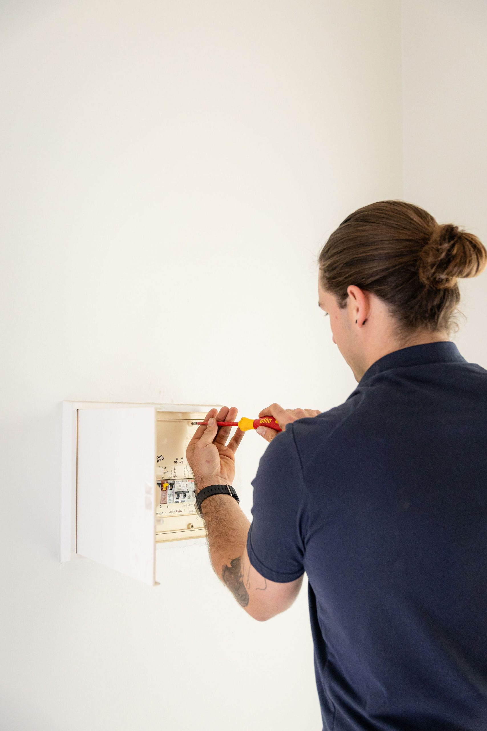An electrician in Perth from Handcock Electrical working on a residential switchboard, ensuring safe and efficient electrical installations.